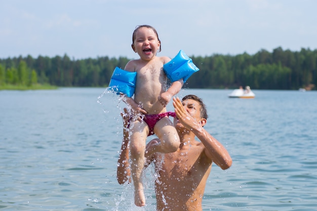 Felice fratello e sorella al mare divertendosi e spruzzi d'acqua in estate