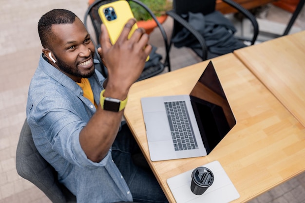 Felice gioioso studente freelance maschio afroamericano che utilizza un computer portatile moderno che tiene una riunione video