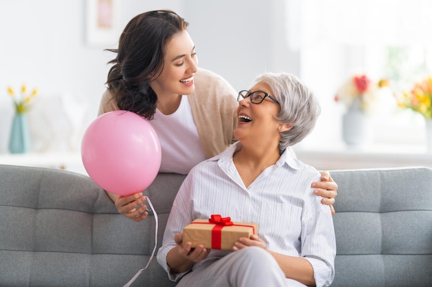 Felice giorno della donna Bella giovane donna e sua madre con palloncini d'aria a casa