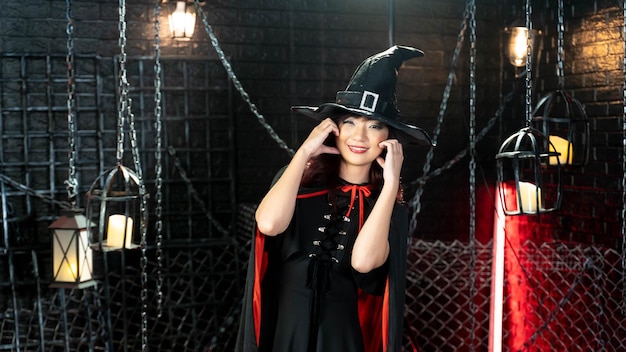 Felice giorno di halloween Giovane modello asiatico bella donna vestita come un costume da strega sorridente in tema haloween