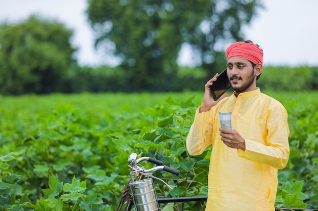 Felice giovane agricoltore indiano che conta e mostra denaro