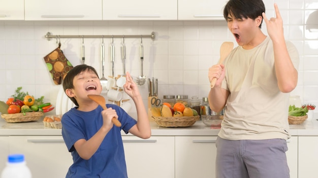 Felice giovane asiatico padre e figlio che fanno colazione insieme giocoso in cucina a casa