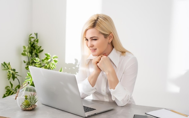 Felice giovane bella donna utilizzando laptop, al chiuso su sfondo bianco muro