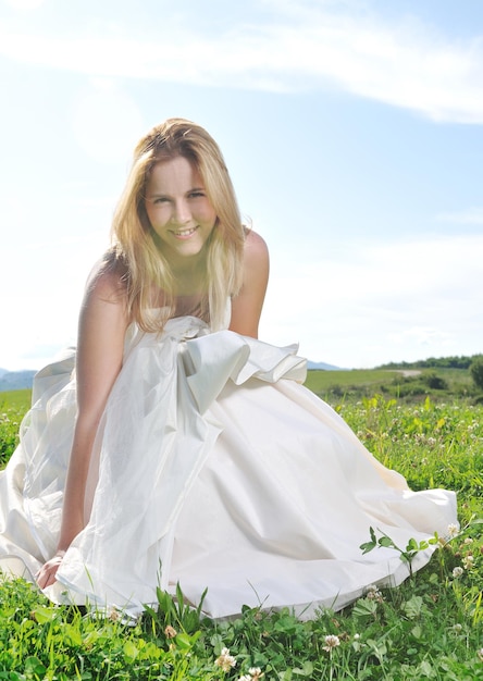 felice giovane bella sposa dopo l'evento cerimonia di nozze divertirsi all'aperto sul prato al tramonto