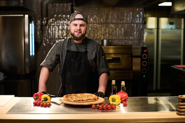 Felice giovane chef e proprietario di ristorante o pizzeria che guarda l'obbiettivo