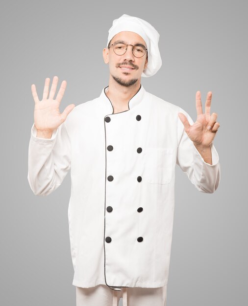 Felice giovane chef facendo un gesto numero otto con le mani