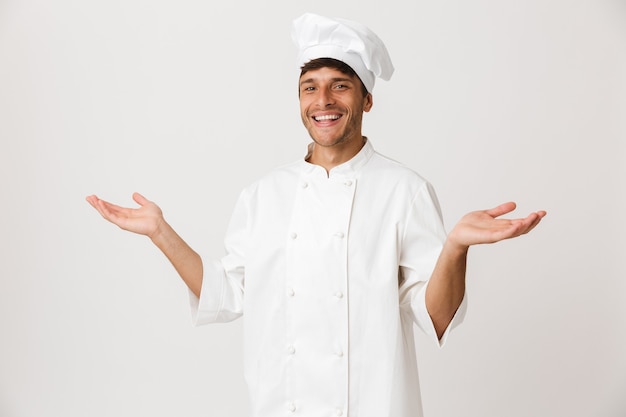 Felice giovane chef isolato su bianco che mostra copyspace.