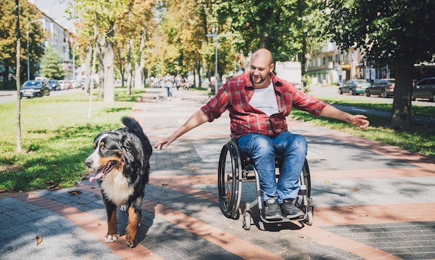 Felice giovane con disabilità fisica su una sedia a rotelle con il suo cane