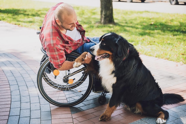 Felice giovane con disabilità fisica su una sedia a rotelle con il suo cane