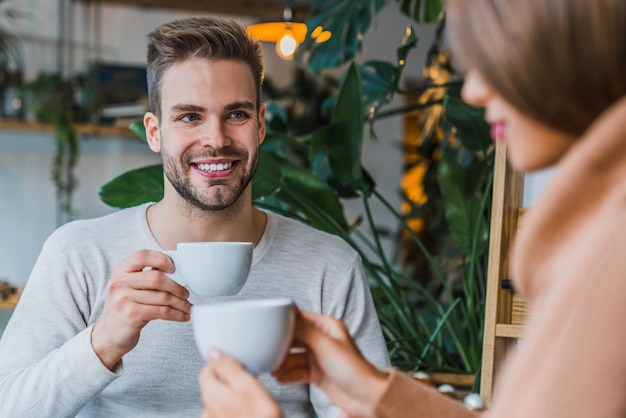 Felice giovane coppia che beve caffè e sorride mentre è seduto al bar