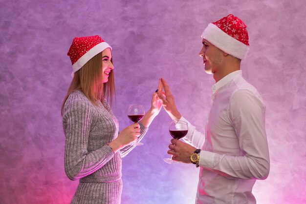 Felice, giovane coppia con bicchieri di vino e cappelli di Babbo Natale che celebra il giorno di San Valentino