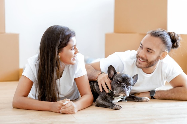 Felice giovane coppia multiculturale con il loro cane che si trasferisce in una nuova casa