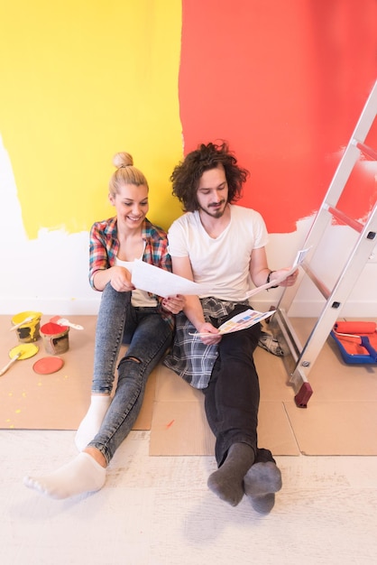 Felice giovane coppia rilassante dopo aver dipinto una stanza nella loro nuova casa sul pavimento