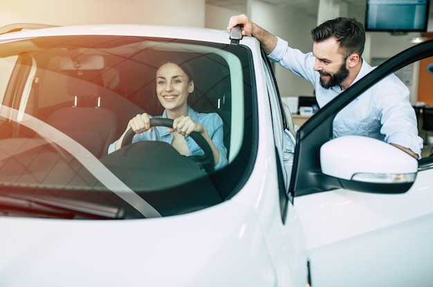 Felice giovane coppia sceglie e acquista una nuova auto per la famiglia nella concessionaria