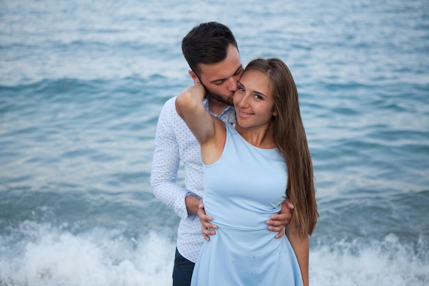 Felice giovane coppia sulla spiaggia innamorata che abbraccia e abbraccia sorridente