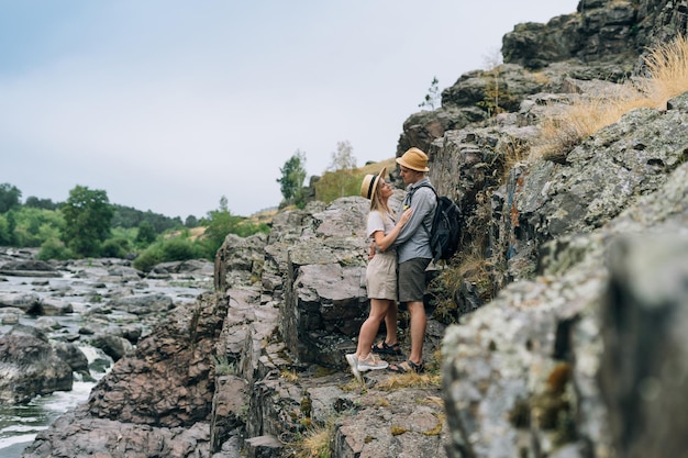 Felice giovane coppia viaggiatori in abiti casual sullo sfondo del fiume di montagna Viaggio di fine settimana turistico locale