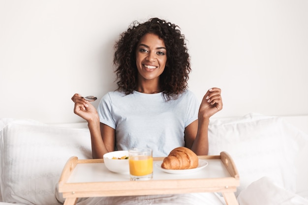 Felice giovane donna africana con una gustosa colazione