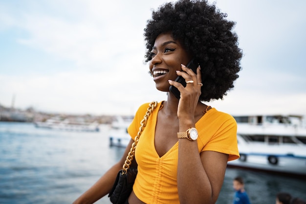 Felice giovane donna afroamericana che parla con il cellulare in città