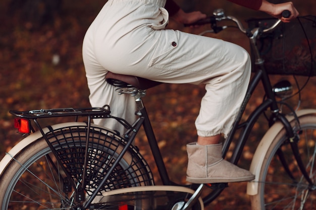 Felice giovane donna attiva in bicicletta nel parco autunnale.