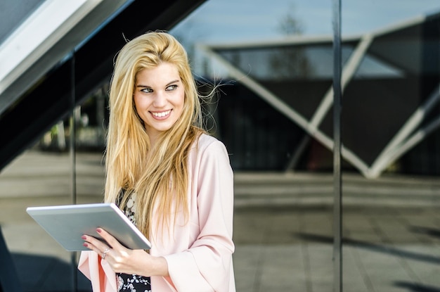 Felice giovane donna bionda all'aperto utilizzando il suo tablet