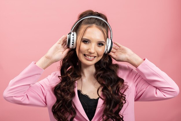 Felice giovane donna bruna ragazza in giacca rosa in posa su sfondo pastello parete studio