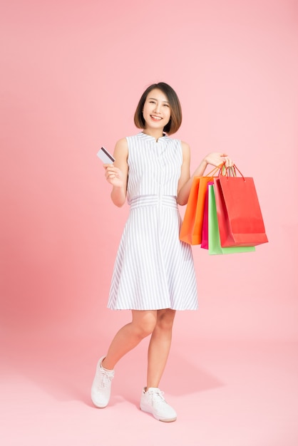 Felice giovane donna casual con sacchetti di carta e carta di credito in plastica