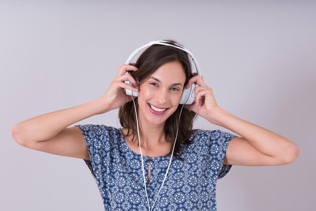 Felice giovane donna che ascolta e ascolta musica con le cuffie isolate su uno sfondo bianco