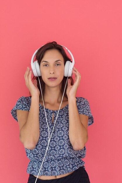 Felice giovane donna che ascolta e ascolta musica con le cuffie isolate su uno sfondo rosso