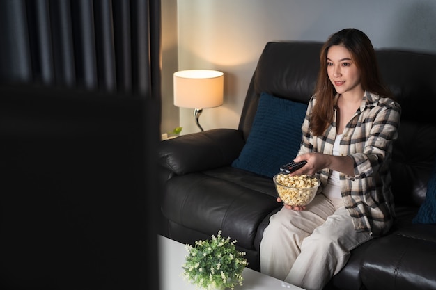 Felice giovane donna che guarda la TV sul divano di notte