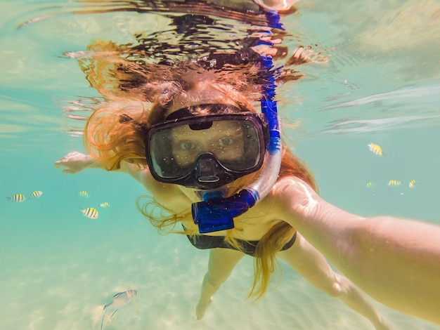 Felice giovane donna che nuota sott'acqua nell'oceano tropicale