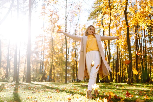 felice giovane donna che si diverte con le foglie nella sosta di autunno