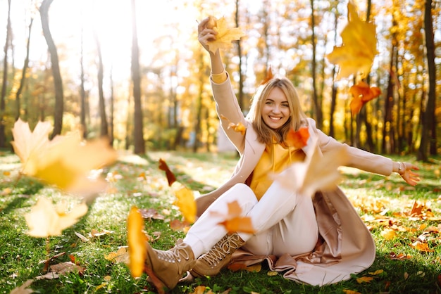 felice giovane donna che si diverte con le foglie nella sosta di autunno