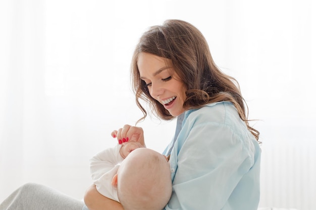 Felice giovane donna che tiene per mano il suo bambino neonato.