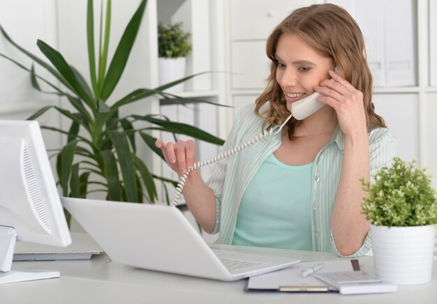 Felice giovane donna con laptop e telefono