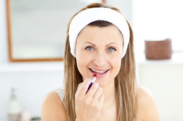 Felice giovane donna con un rossetto rosso in bagno