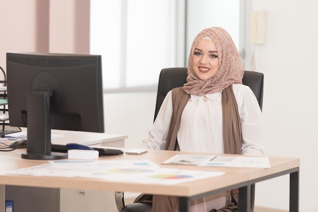 Felice giovane donna d'affari musulmana lavora in un ufficio moderno sul computer