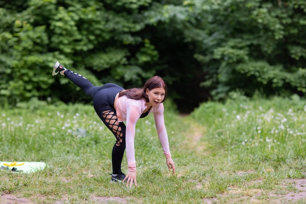 Felice giovane donna facendo alcuni esercizi di stretching al parco.