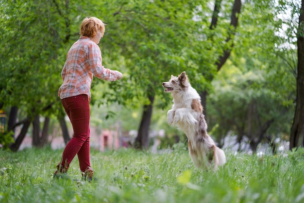 Felice giovane donna fare jogging con il suo cane nel parco.