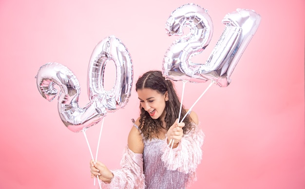 Felice giovane donna in abito festivo in posa tenendo palloncini d'argento per il concetto di nuovo anno