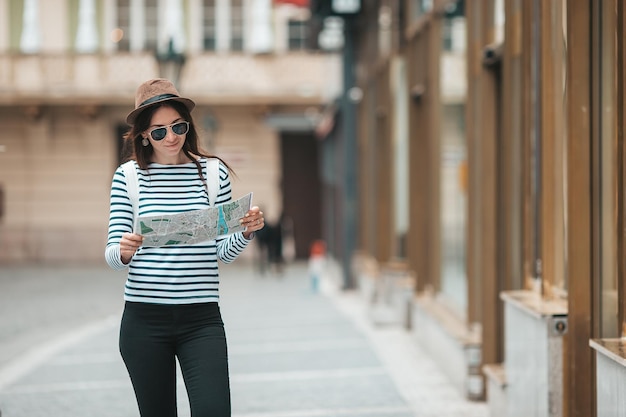 Felice giovane donna in cappello sulla strada della città europea