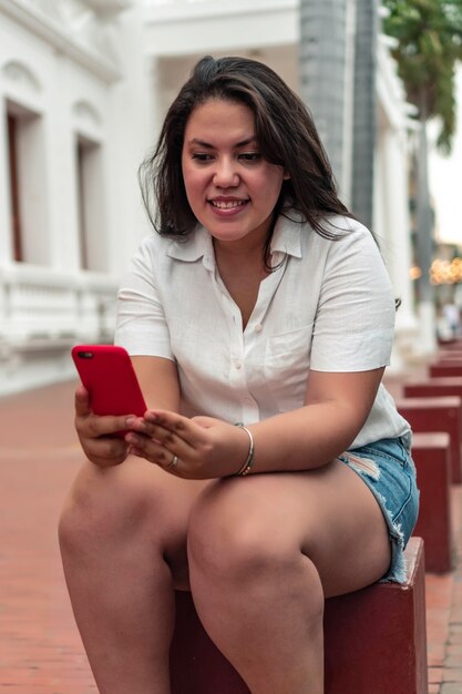 Felice giovane donna in città che controlla il suo cellulare