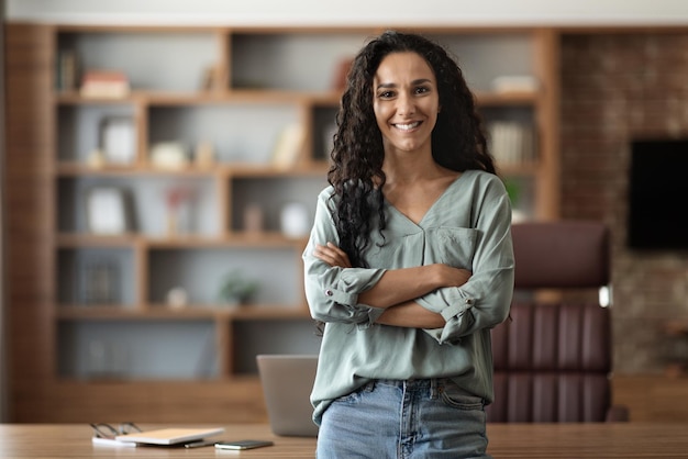 Felice giovane donna in posa in ufficio sorridente alla telecamera