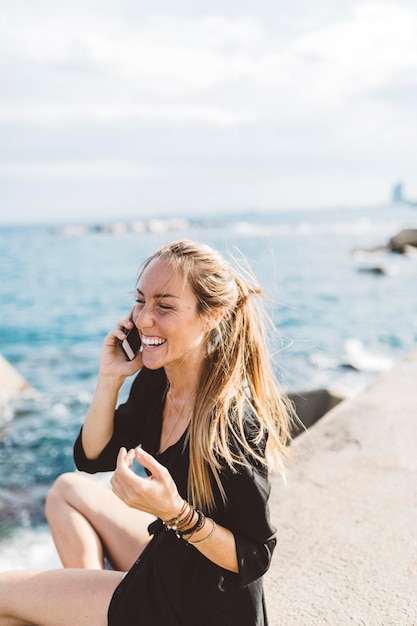 Felice giovane donna in riva al mare sul cellulare