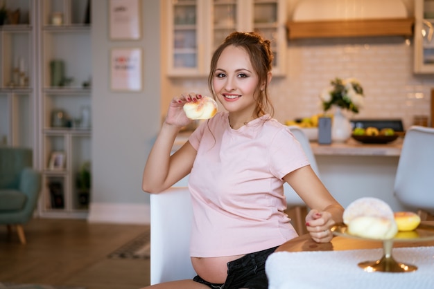 Felice giovane donna incinta con la torta in mano in cucina