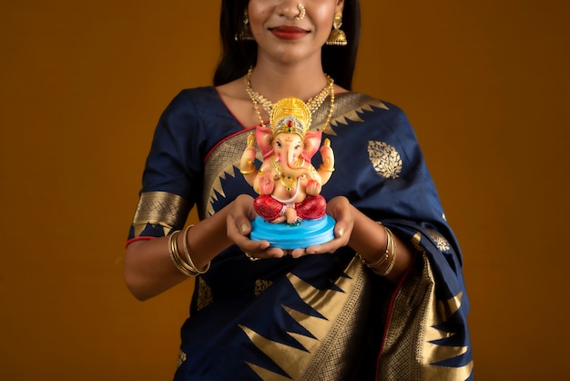 Felice giovane donna indiana in posa con la statua di Ganesha in occasione del Ganesh Festival
