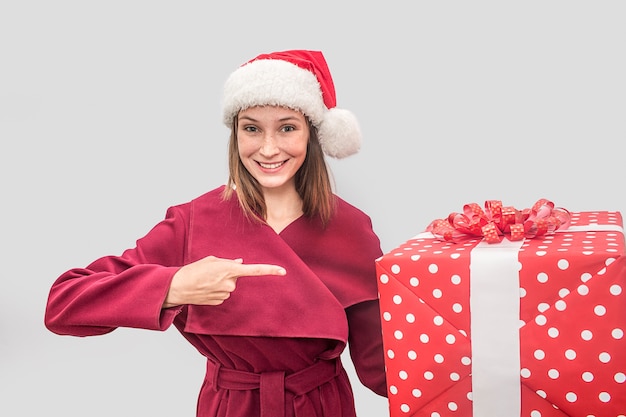 Felice giovane donna indossa un cappotto rosso e un cappello di Natale