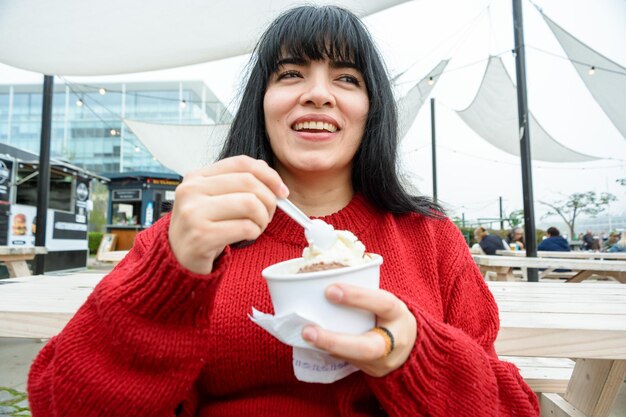 felice giovane donna latina seduta gustando un delizioso gelato a due gusti