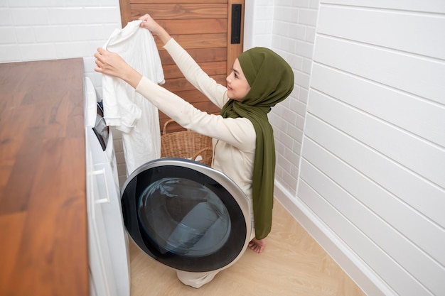 Felice giovane donna musulmana che indossa l'hijab che fa il bucato in casa concetto di stile di vita sano