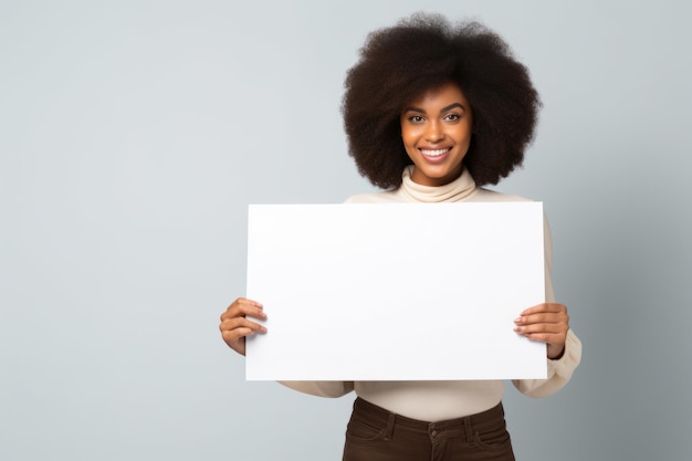 Felice giovane donna nera che tiene un cartello bianco vuoto in un ritratto di studio isolato