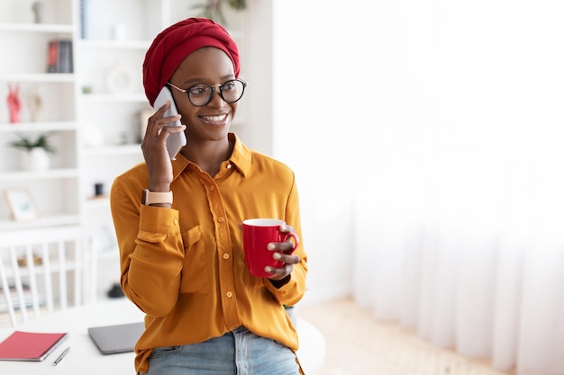 Felice giovane donna nera parlando al telefono avendo pausa caffè